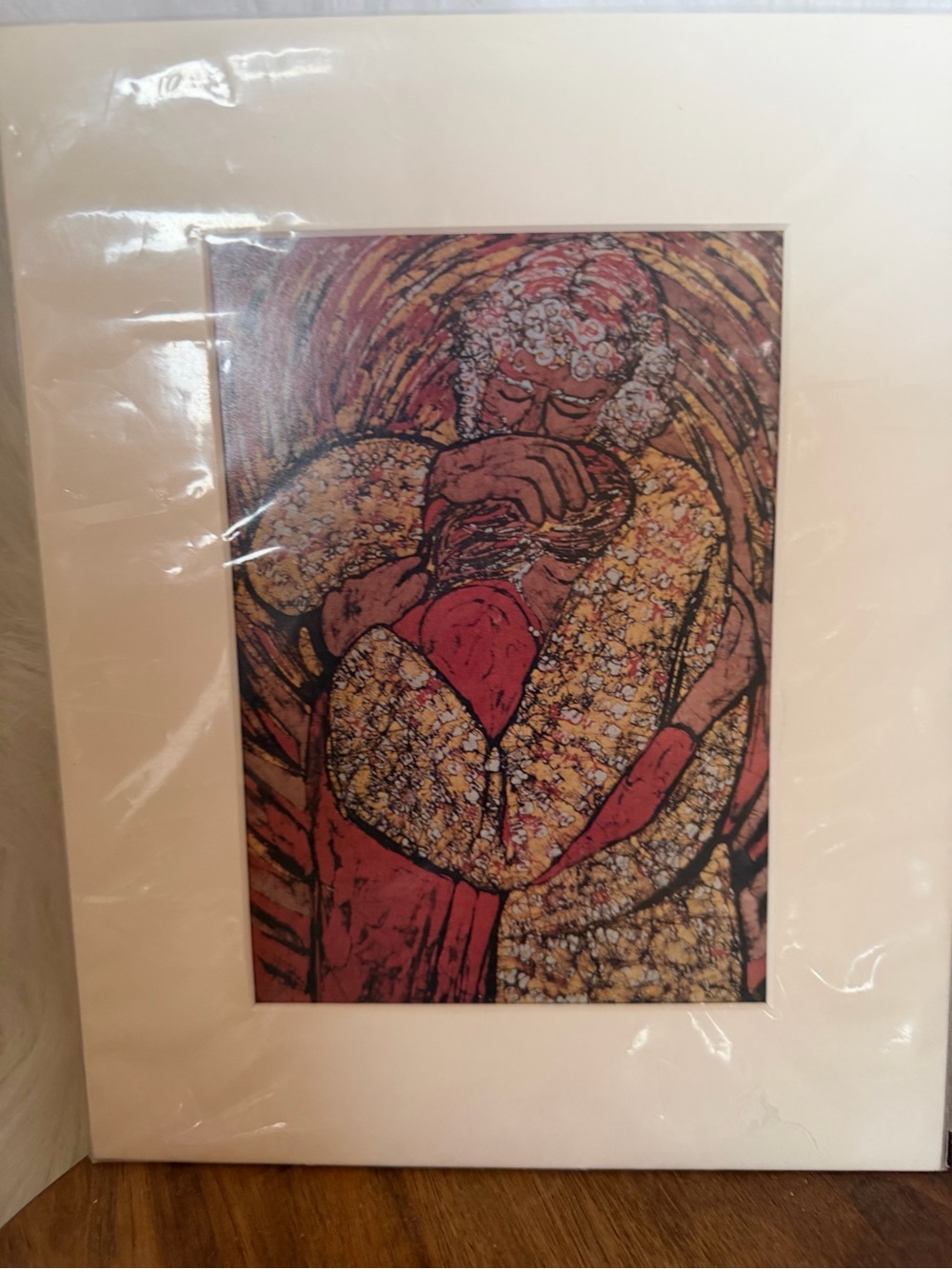 Batik-inspired print of two figures embracing, matted and framed.